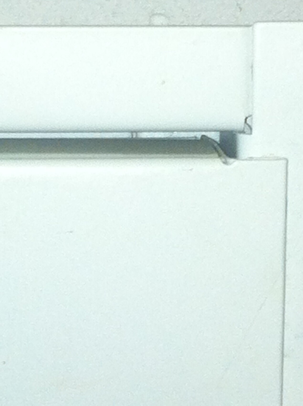 Nahaufnahme eines weißen Fensterrahmens mit Rollladenführung und Klemmstück