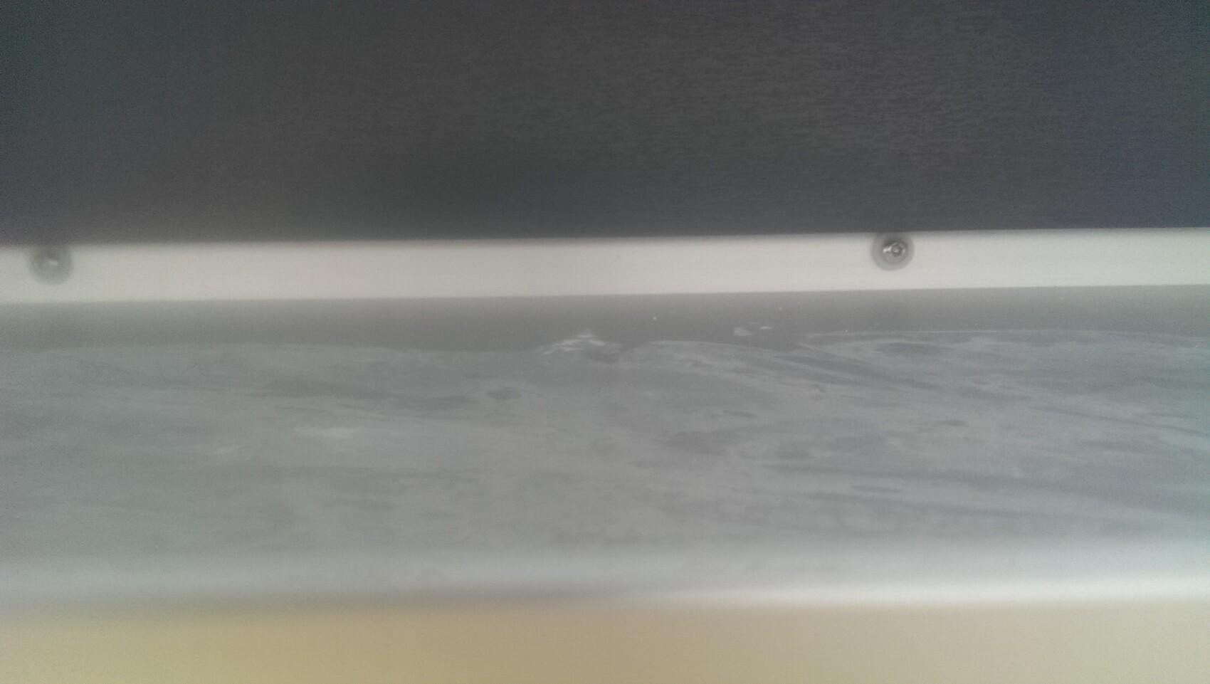 Unterseite eines Fensterrollladens mit Schienen und Schrauben, Blick von unten.