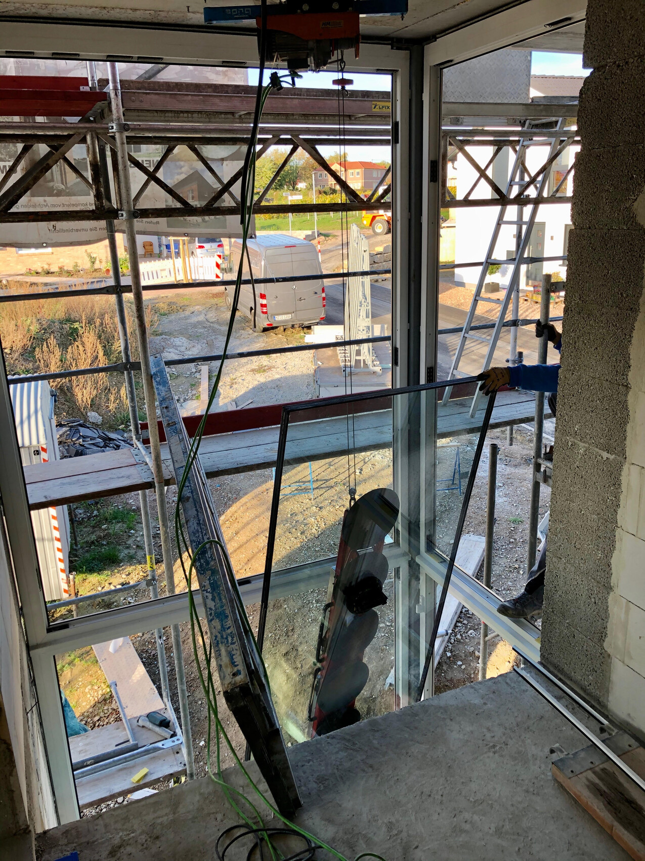 Innenraum einer Baustelle mit Glasfront, Gerüst und Blick auf den Außenbereich