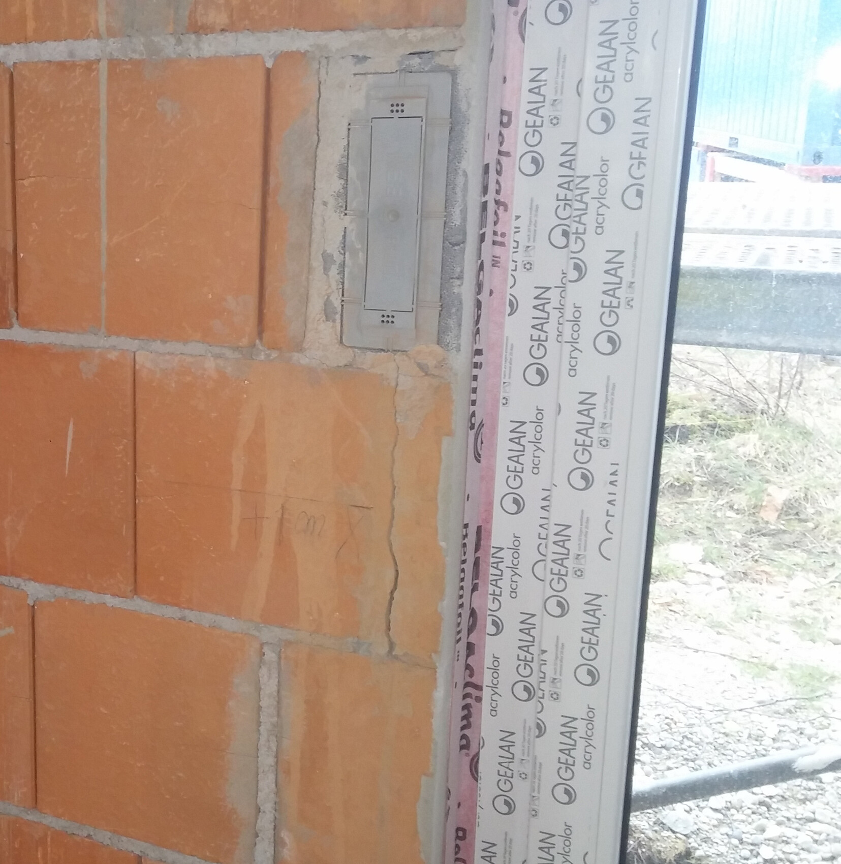 Rohbau-Baustelle: rote Ziegelwand mit Fensterrahmen und GEALAN-Verpackung
