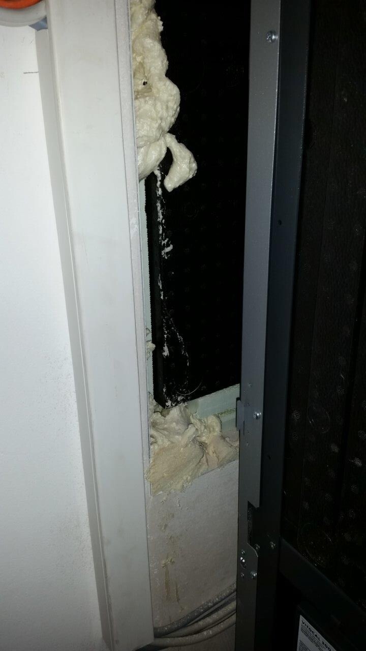 Nahaufnahme eines Türrahmens mit weißem Dämmstoffschaum um den Spalt