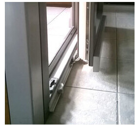 Perspektive auf Türrahmen mit Glasfenster neben Fliesenboden und Metallrahmen.