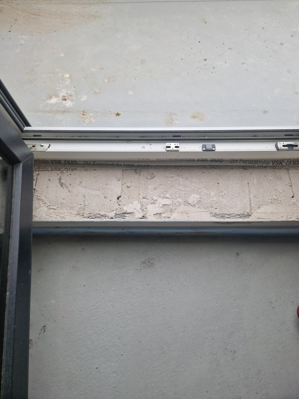 Schiebetür aus Glas geöffnet, Bodenschiene sichtbar, rauer Betonboden draußen