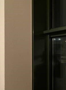 Beige Wand neben dunklem Fensterrahmen im Innenbereich