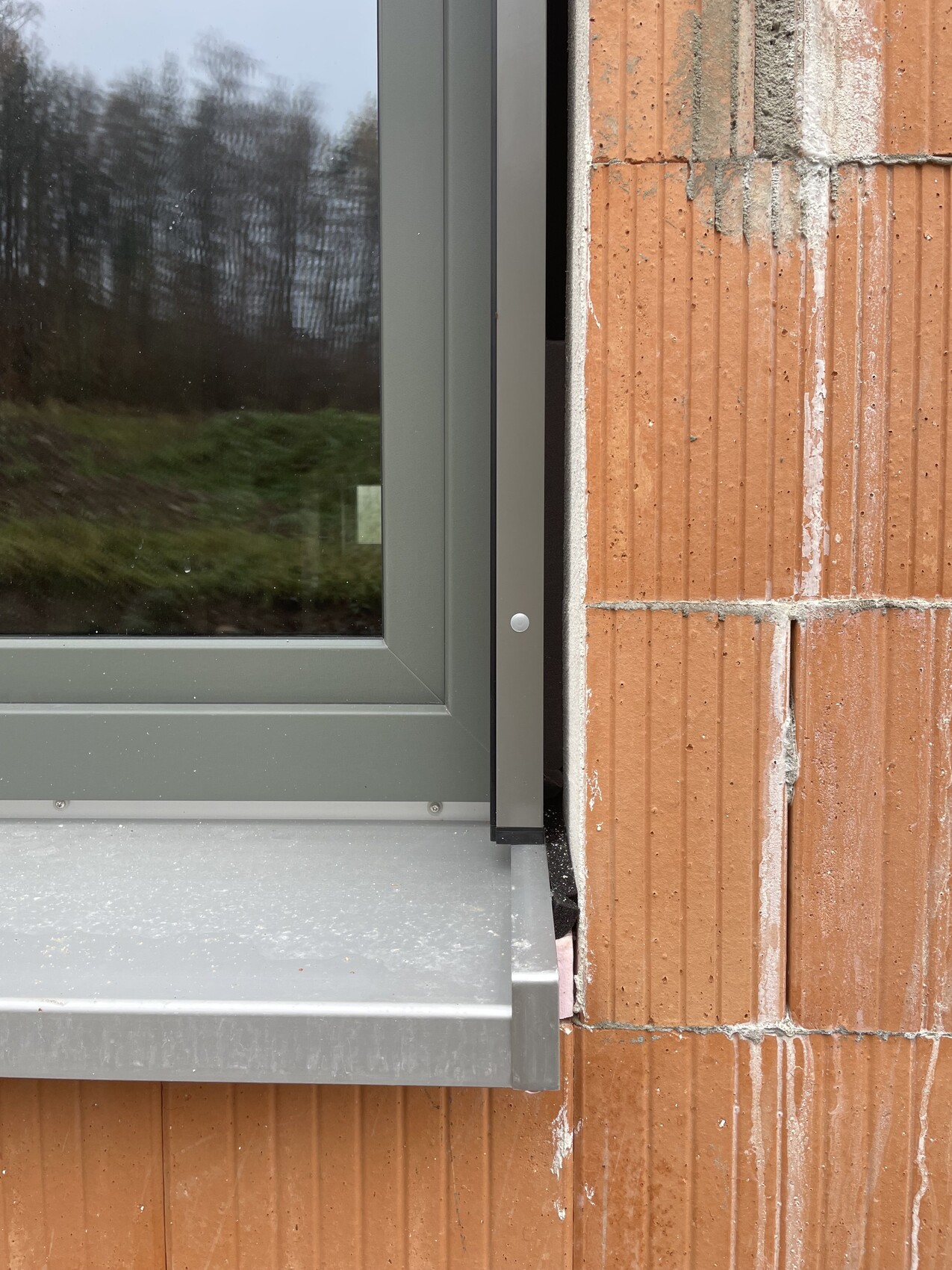 Außenfensterrahmen aus Metall vor roter Ziegelwand an einer Baustelle