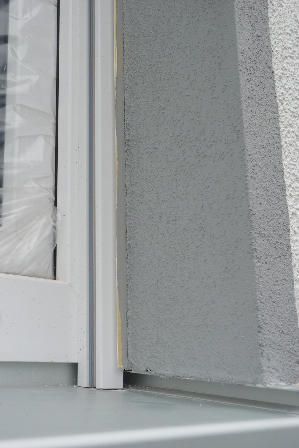 Detailaufnahme eines Fensterrahmens an einer grauen Außenwand