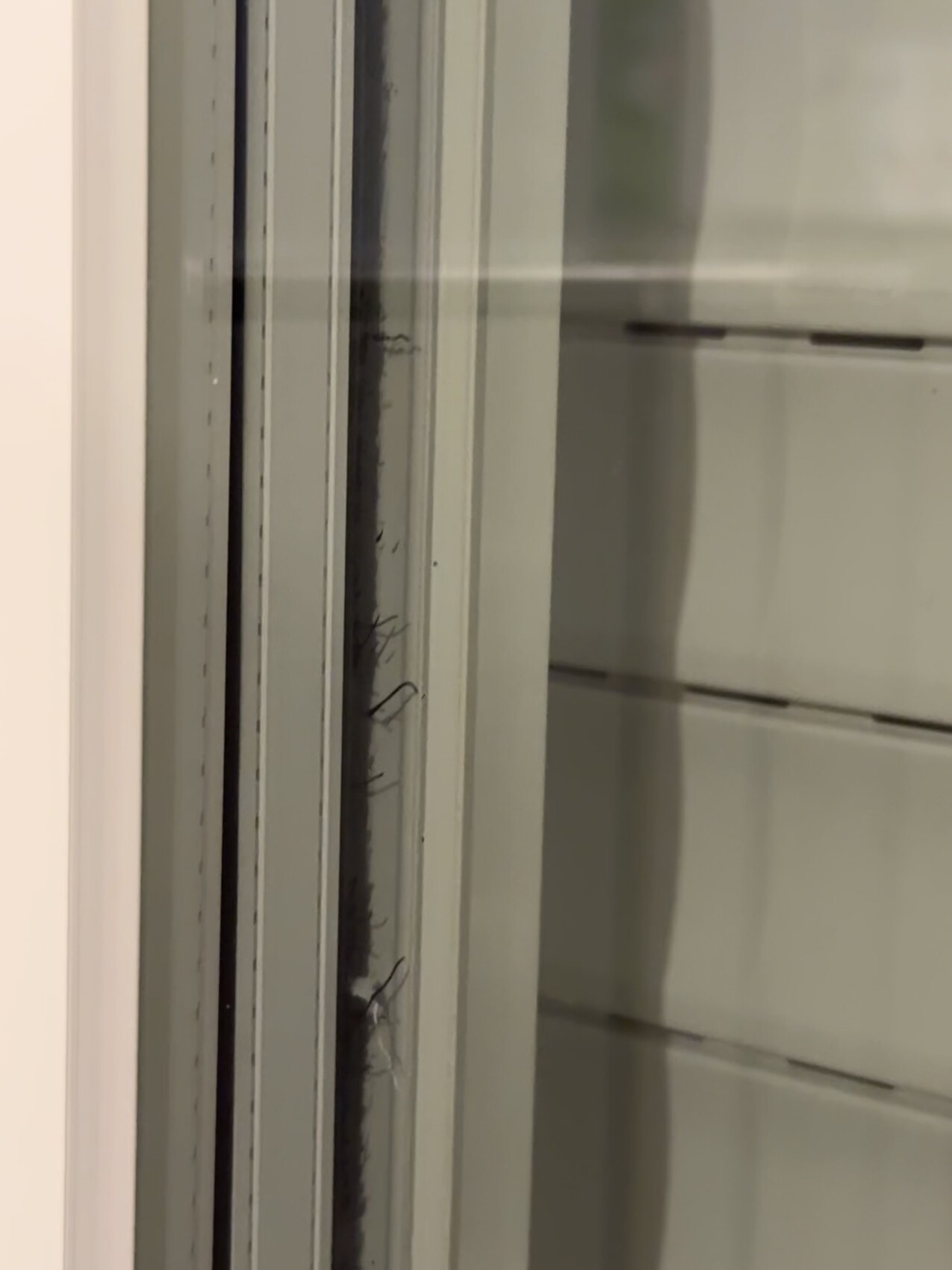 Nahaufnahme eines Fensterrahmens mit Glas, Metallprofilen und einem Spalt.