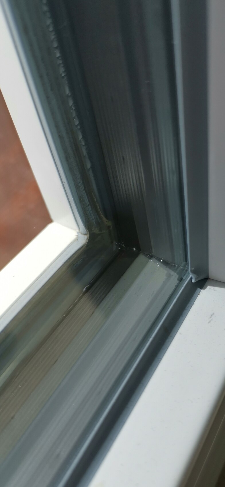 Nahaufnahme eines Fensterrahmens aus Metall mit Dichtung und Glas.