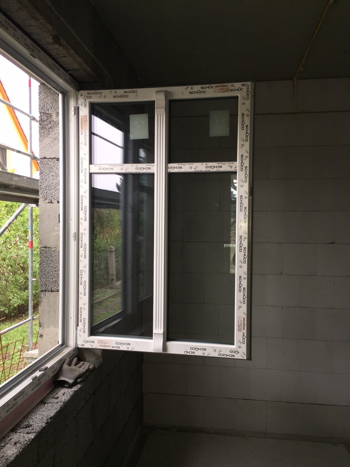 Fensterrahmen aus PVC im Rohbau, Innenraum einer Baustelle mit Sicht auf Mauerwerk