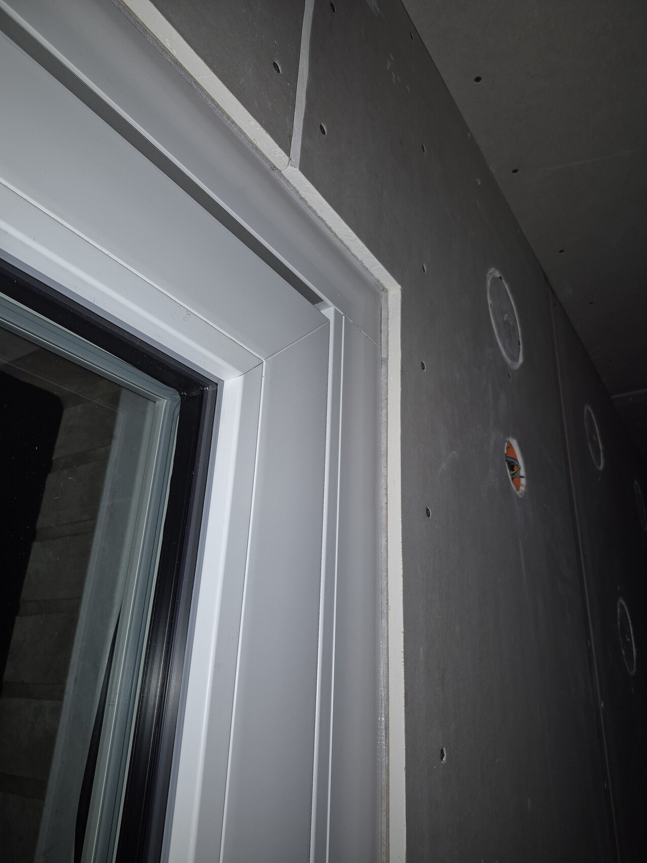 Weißer Fensterrahmen in roher Betonwand während Bauphase