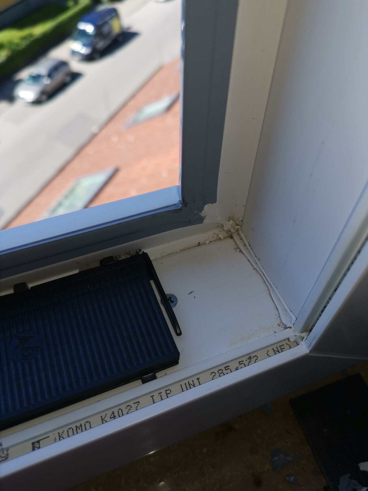 Fensterrahmen innen, Blick nach draußen auf Straße mit geparkten Autos.