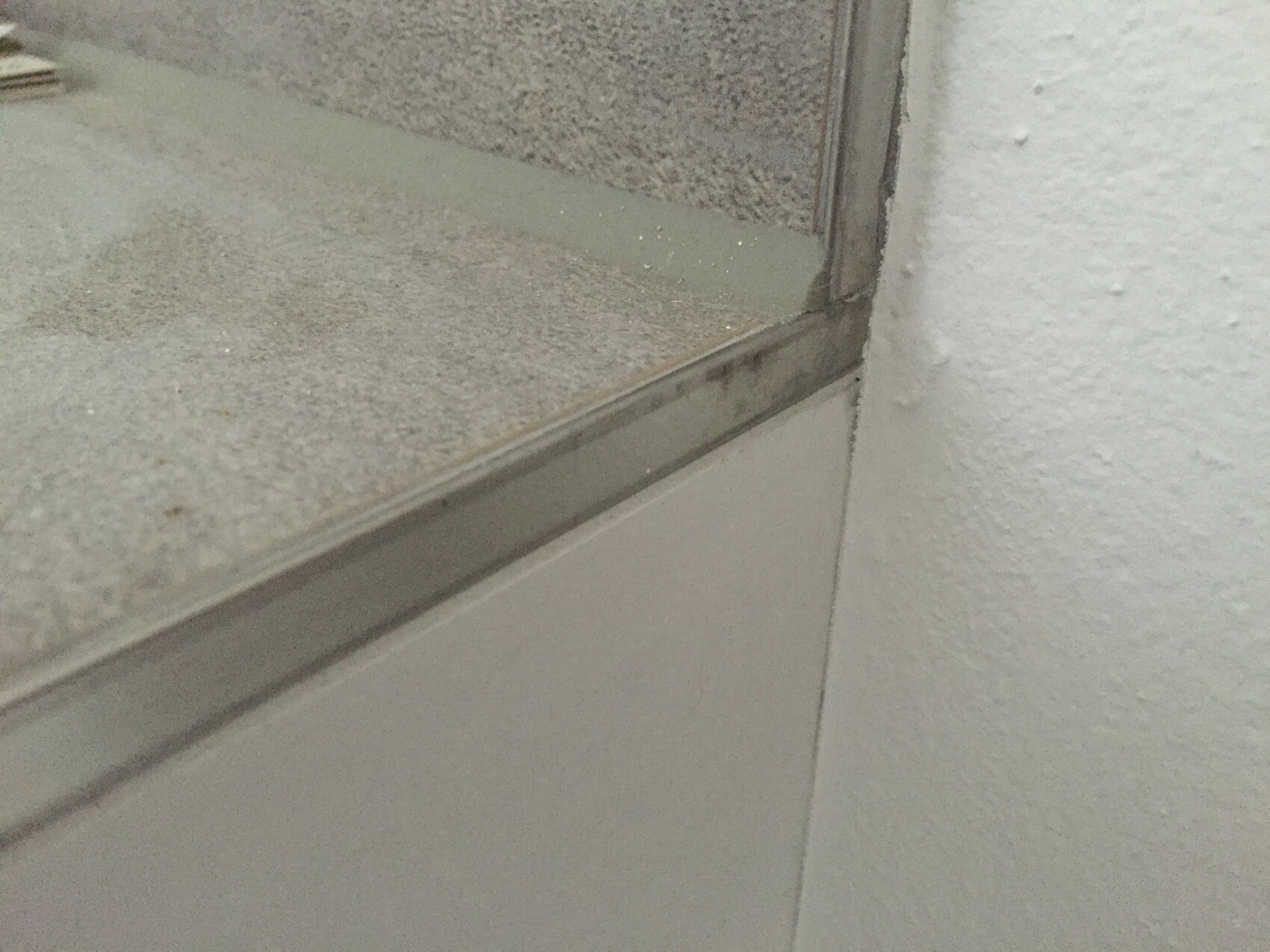 Nahaufnahme eines Fensterrahmens mit Glas, Dichtung und Staub am Rand im Innenraum