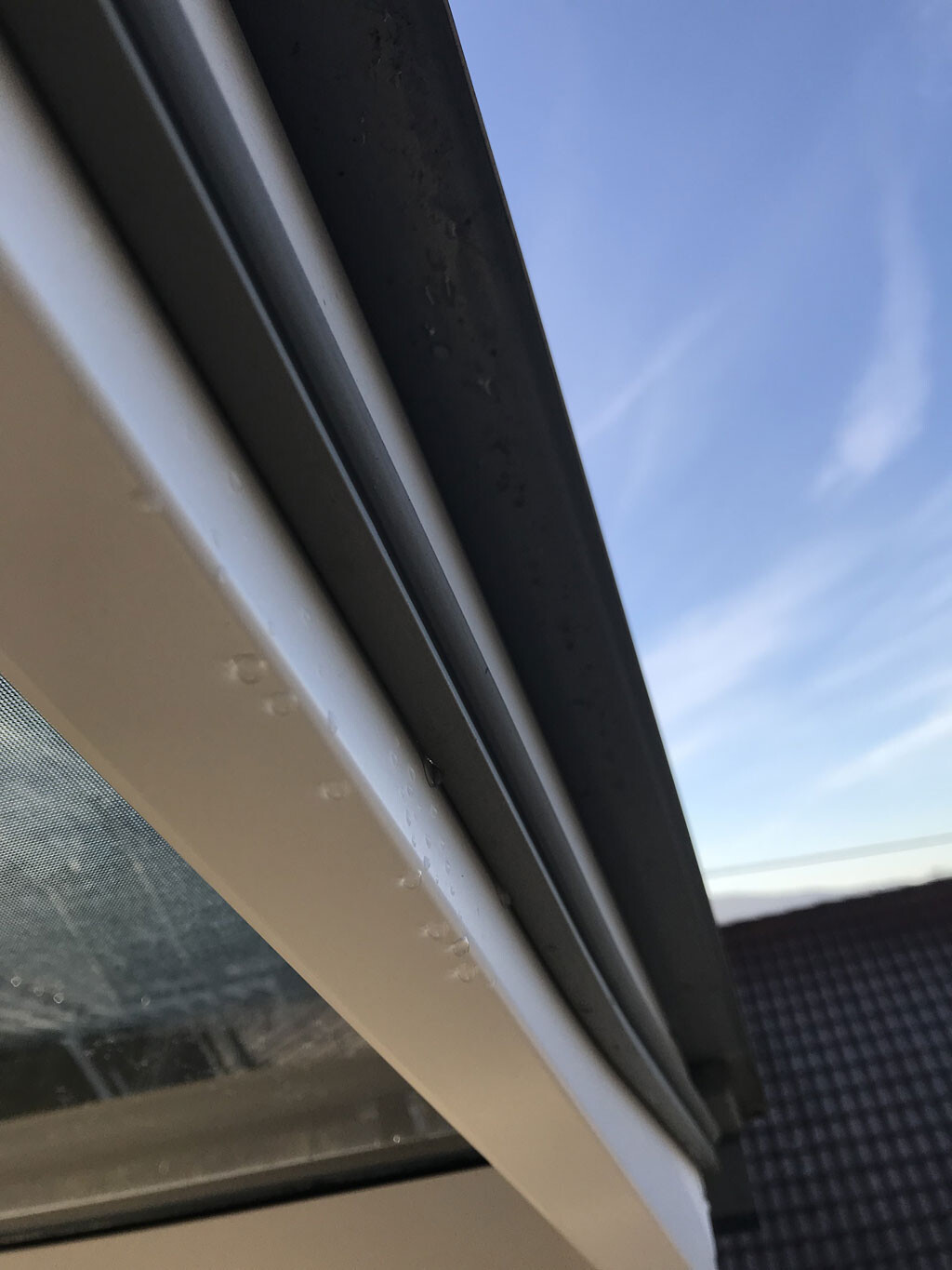 Nahaufnahme eines Fensterrahmens mit Dichtungsprofil, Blick nach draußen zum Himmel.