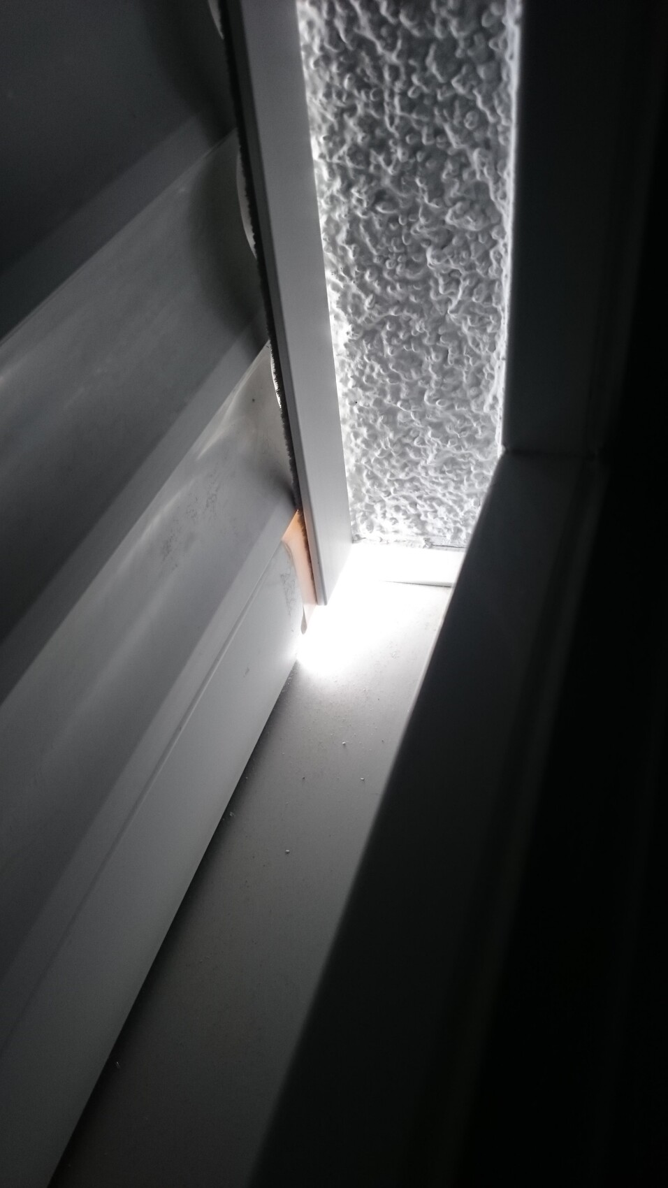 Nahaufnahme eines Fensterrahmens mit Lichtschein durch Spalt und strukturierter Glasoberfläche