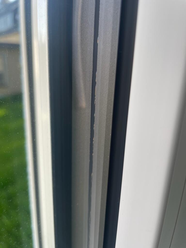 Nahaufnahme eines Fensterrahmens mit Riss in der Dichtung und einem Spalt