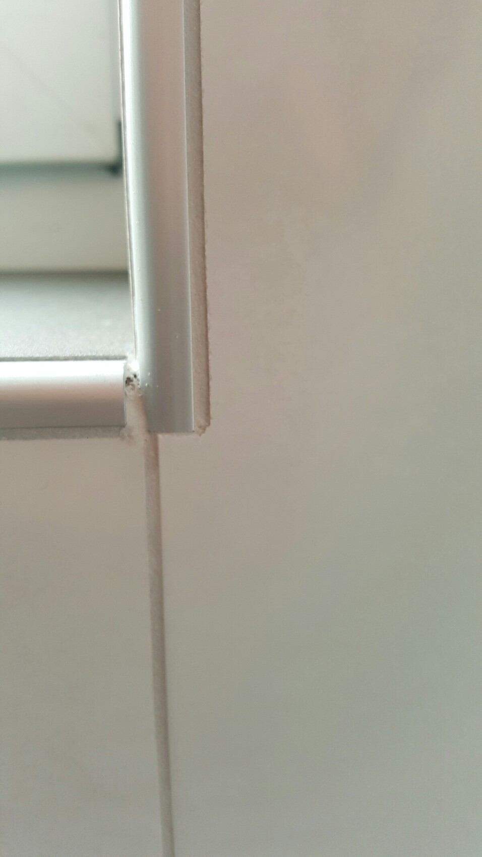Nahaufnahme eines weißen Fensterrahmens mit beschädigten Wandkanten