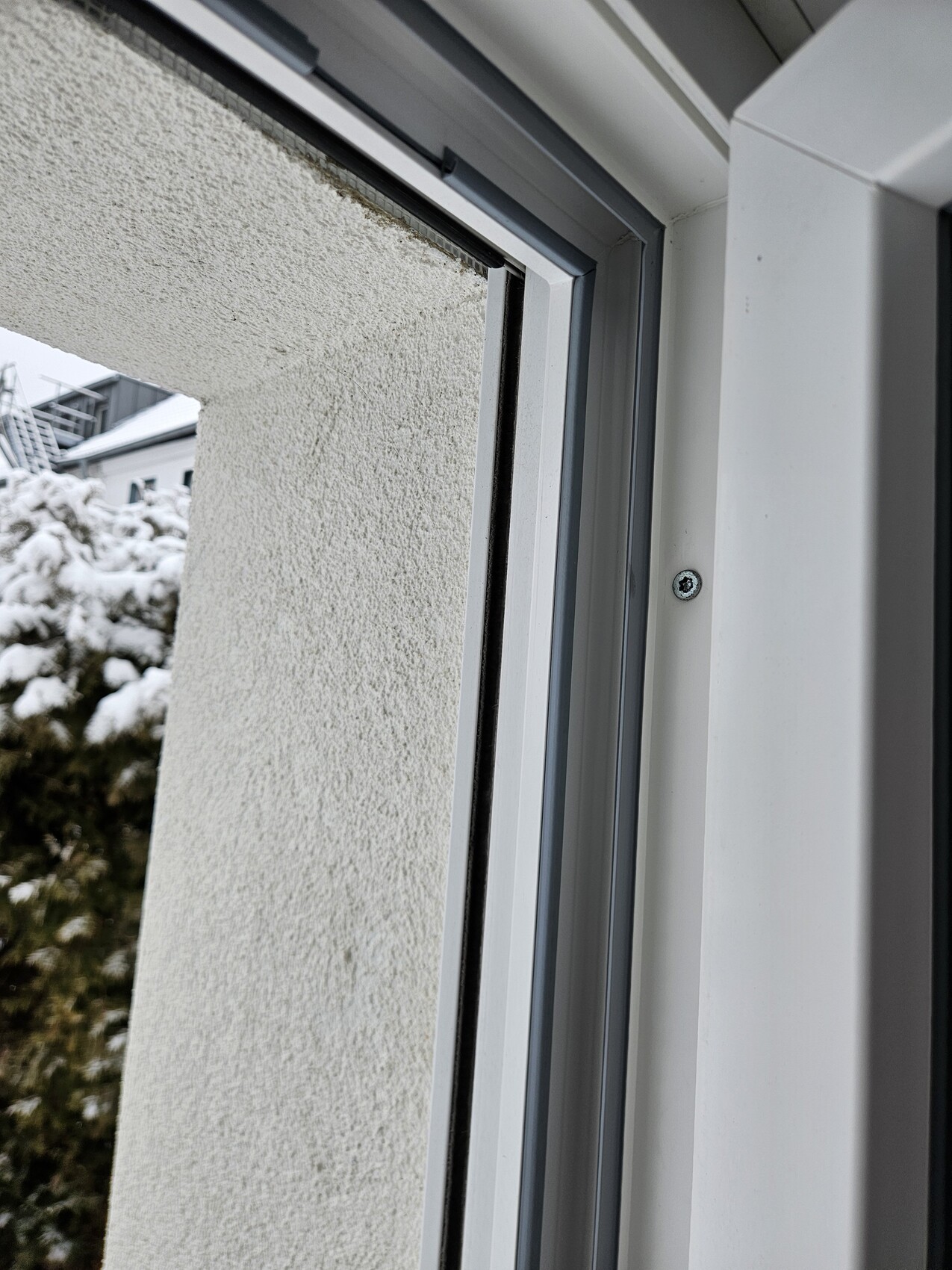 Weißer Kunststoff-Fensterrahmen, geöffnete Fensterfront, verschneite Außenwand im Hintergrund