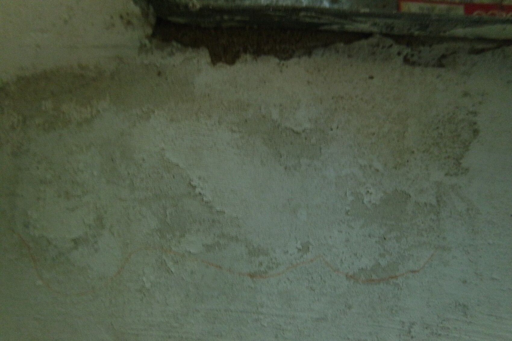 Kellerwand mit feuchten Flecken und abblätterndem Putz in einer Bauumgebung