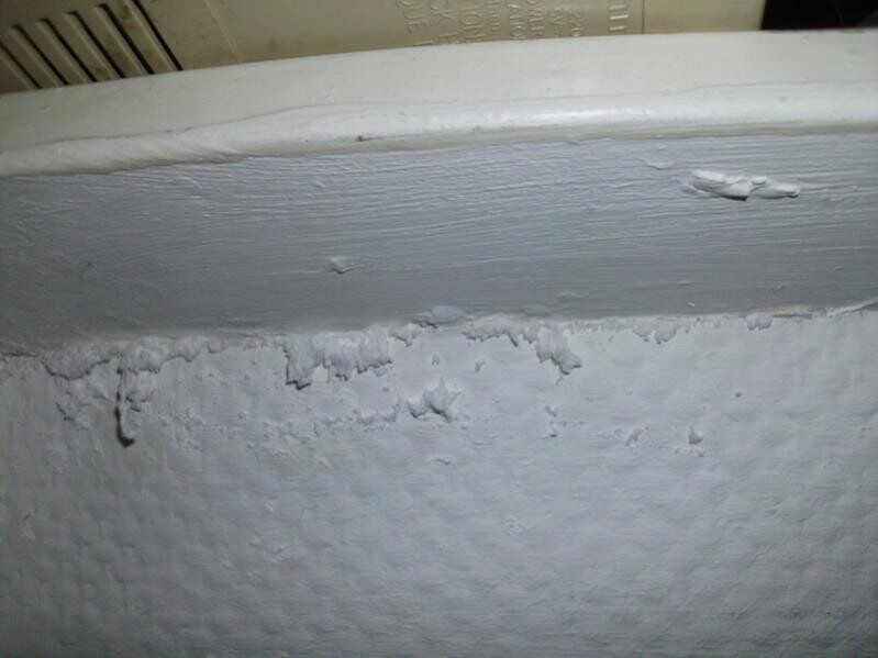 Feuchte Wand mit abplatzendem Putz unter Badewannenrand
