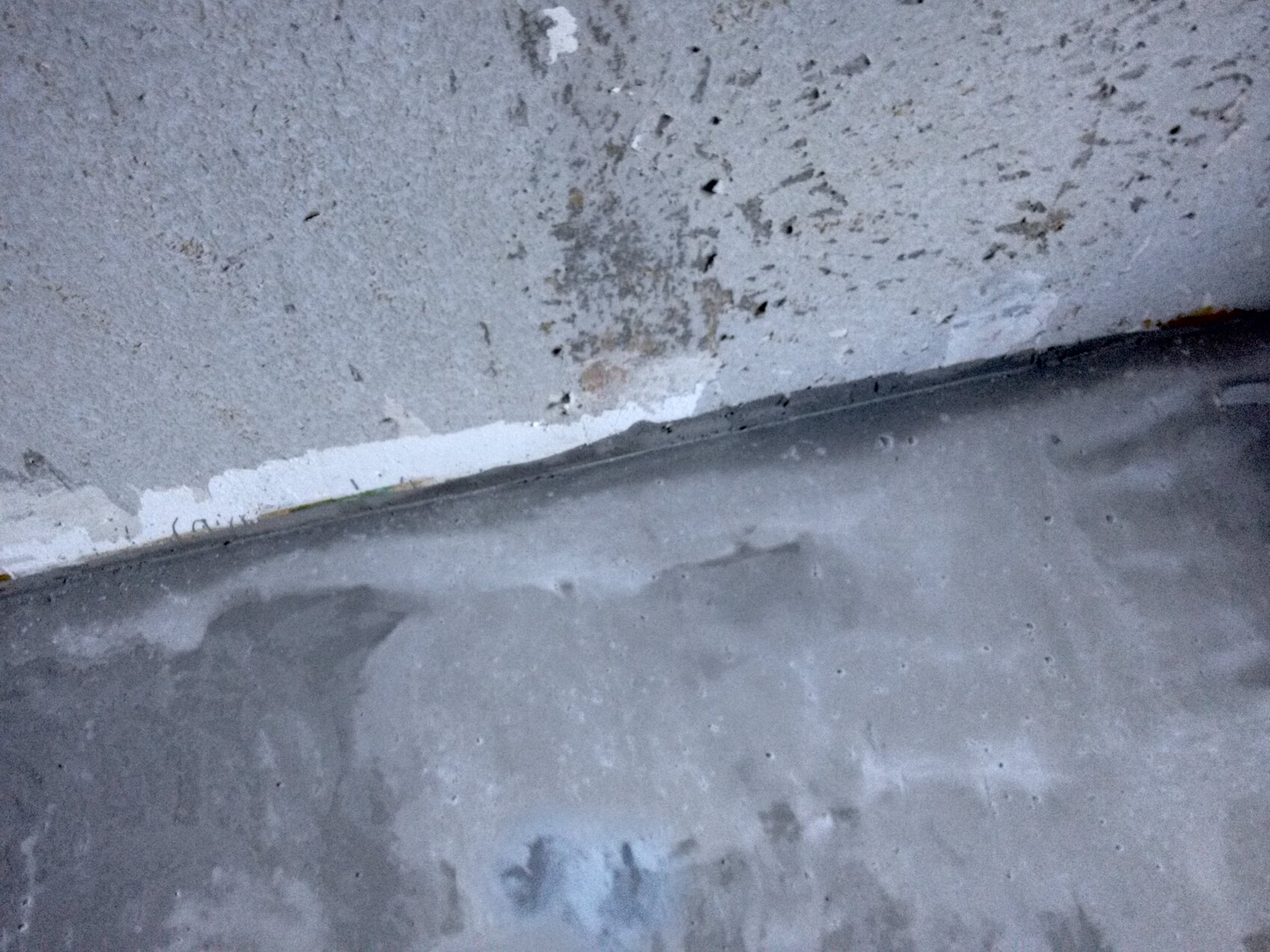 Kellerwand und Boden mit Feuchtigkeitsspuren und Putzabplatzungen