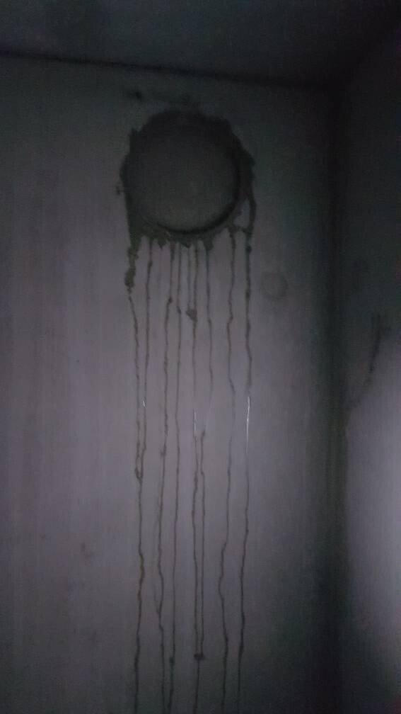 Dunkler Innenraum mit runder dunkler Verfärbung an der Wand und langen Tropfen, die nach unten laufen.