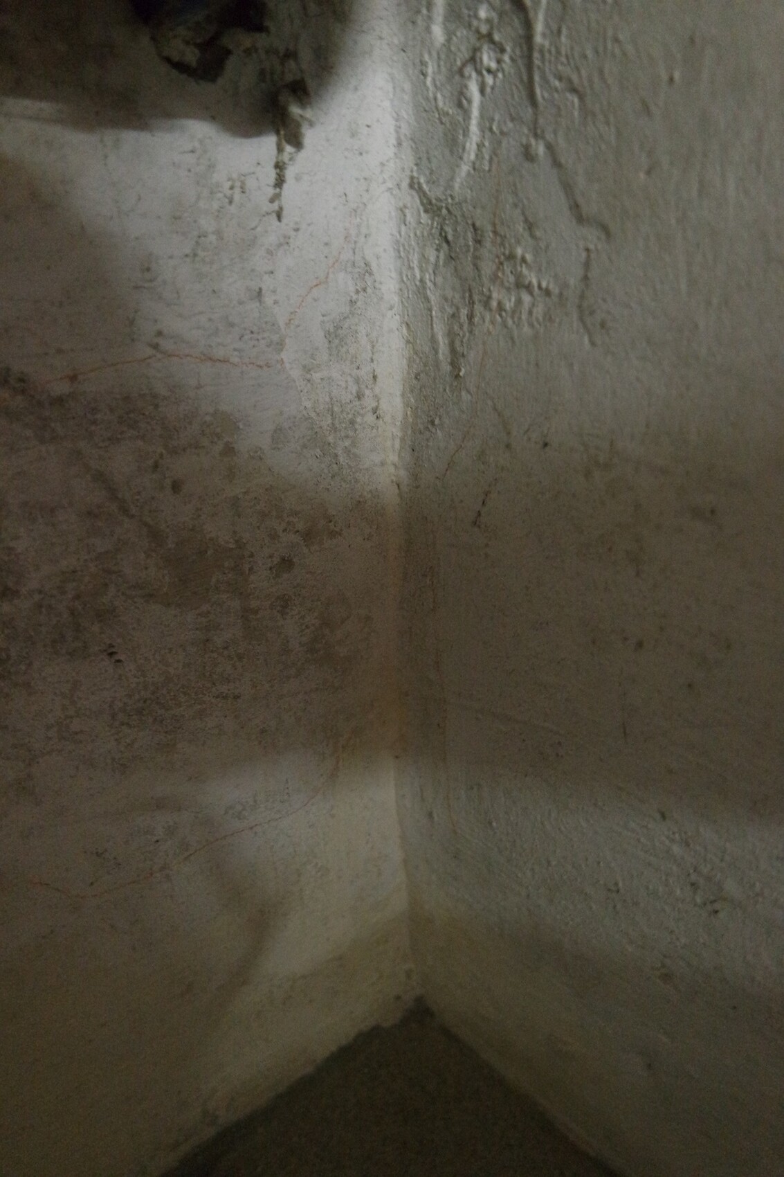 Eckige feuchte Kellerwand mit rauer Putzoberfläche und Feuchtigkeitsspuren