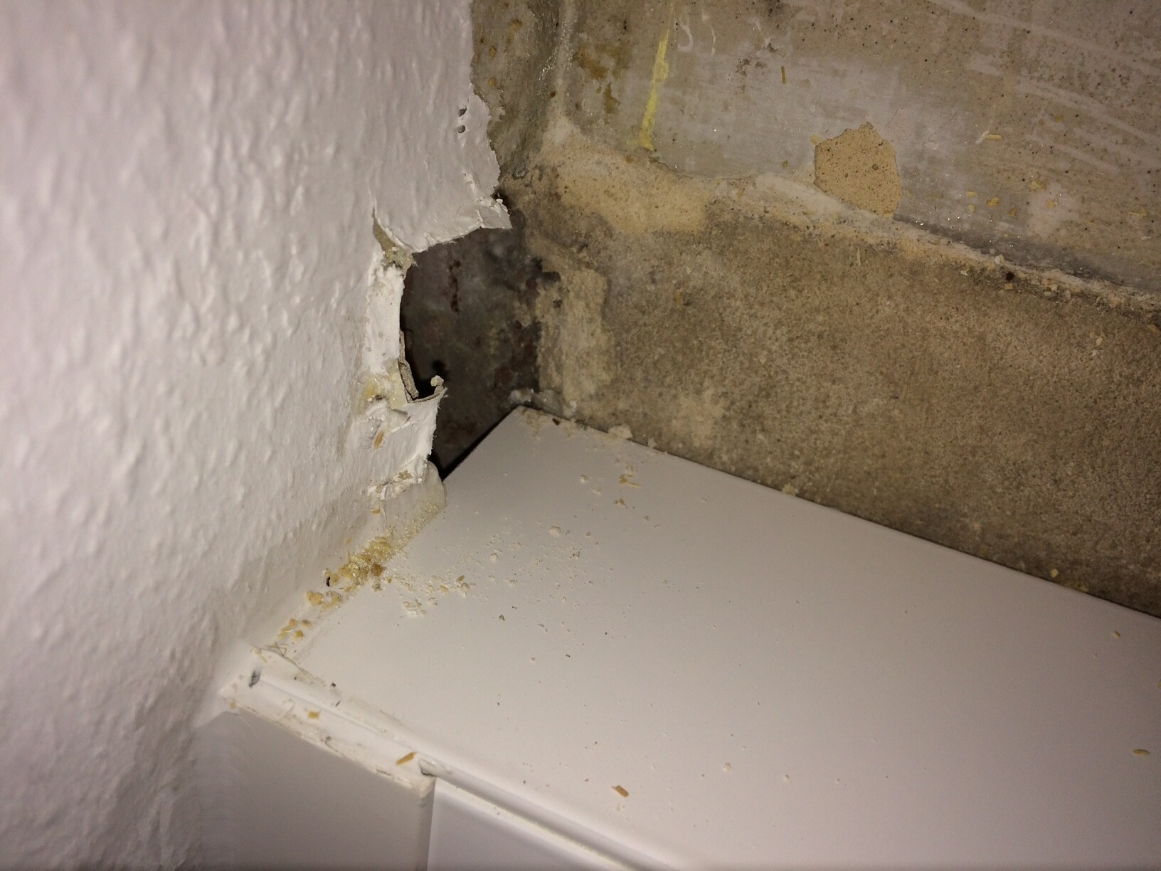 Beschädigte Wand-Ecke mit Putzabplatzung und Feuchtigkeit
