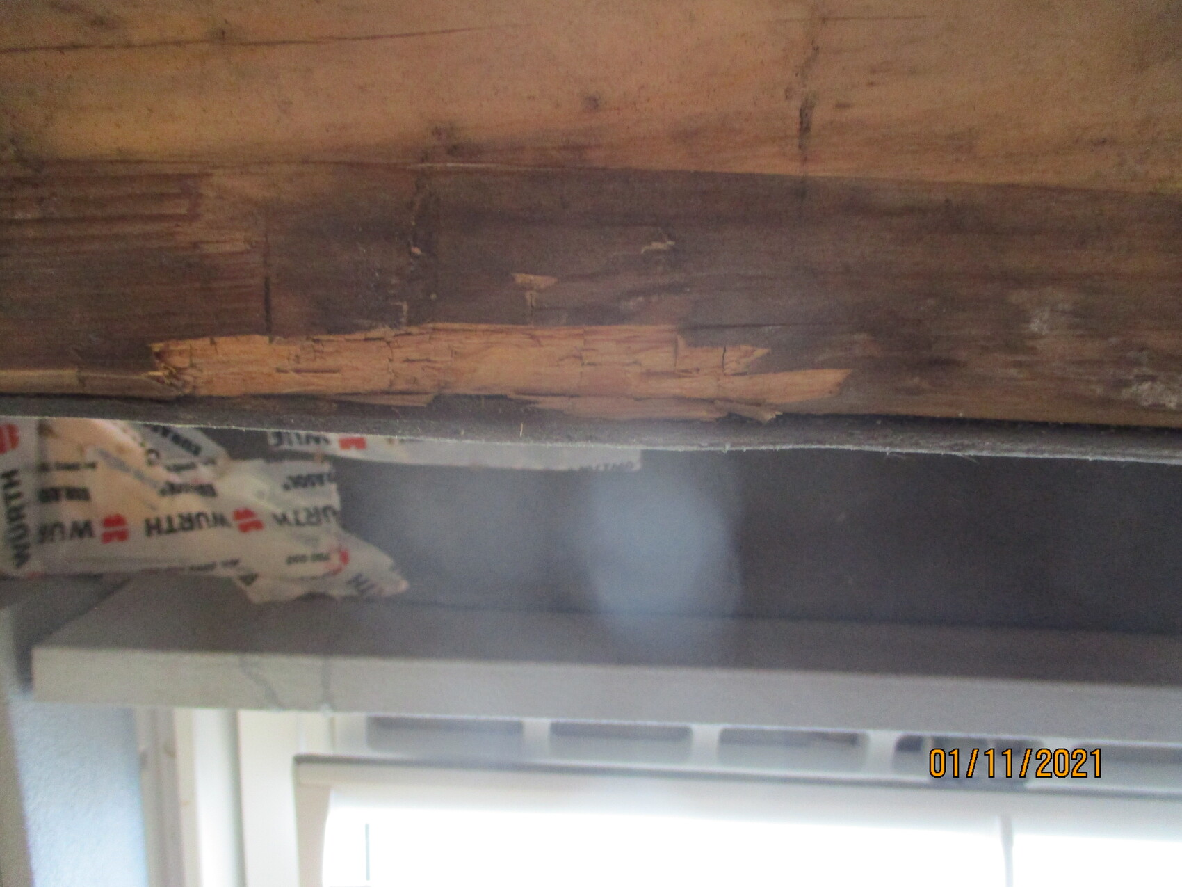 Holzbohlen mit abblätternder Oberfläche über Fenster; links Verpackungsmaterial, Datum 01/11/2021