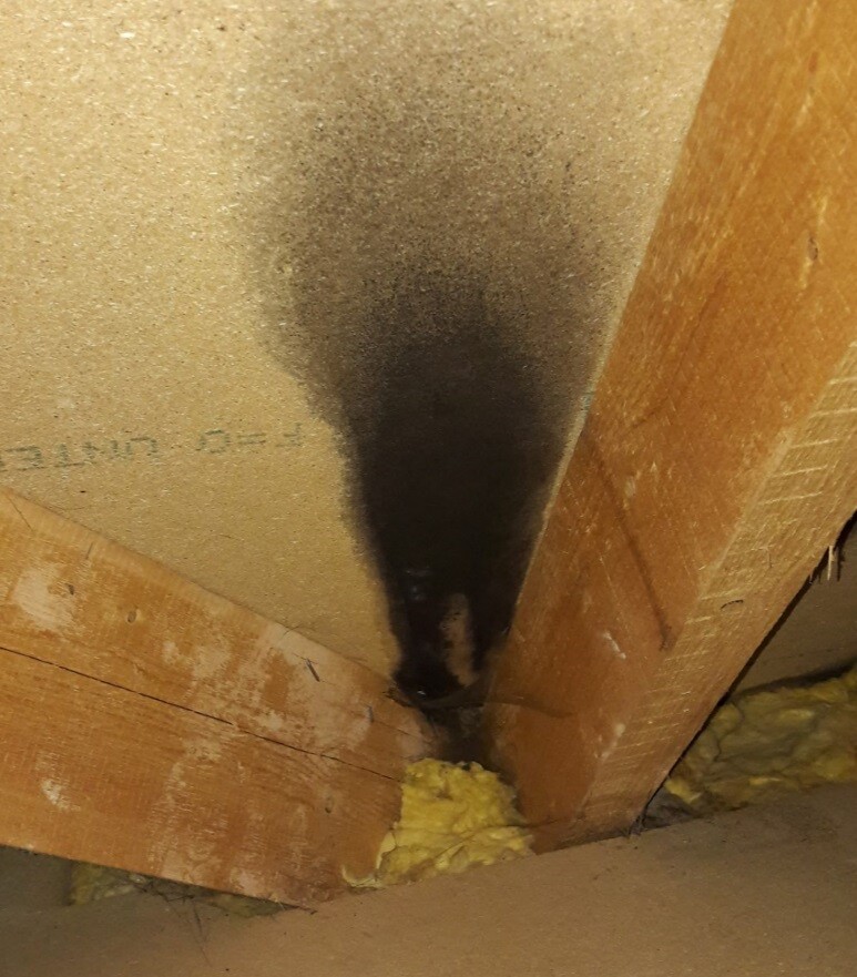 Feuchtigkeitsspur im Dachstuhl neben Gelb-Dämmmaterial und Holzbalken