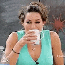 Frau in hellblauem Top trinkt aus einer Tasse während einer Fernsehsendung