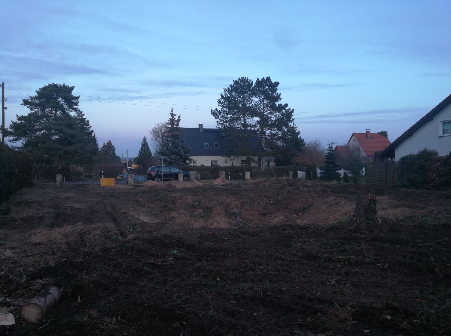 Leere Baufläche in Vorstadt, Erde, Bäume und Häuser im Hintergrund.