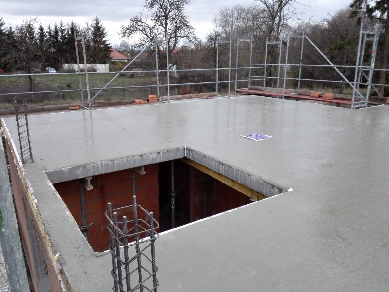 Frisch gegossene Betondecke auf Baustelle, Loch in der Platte, umlaufendes Gerüst.