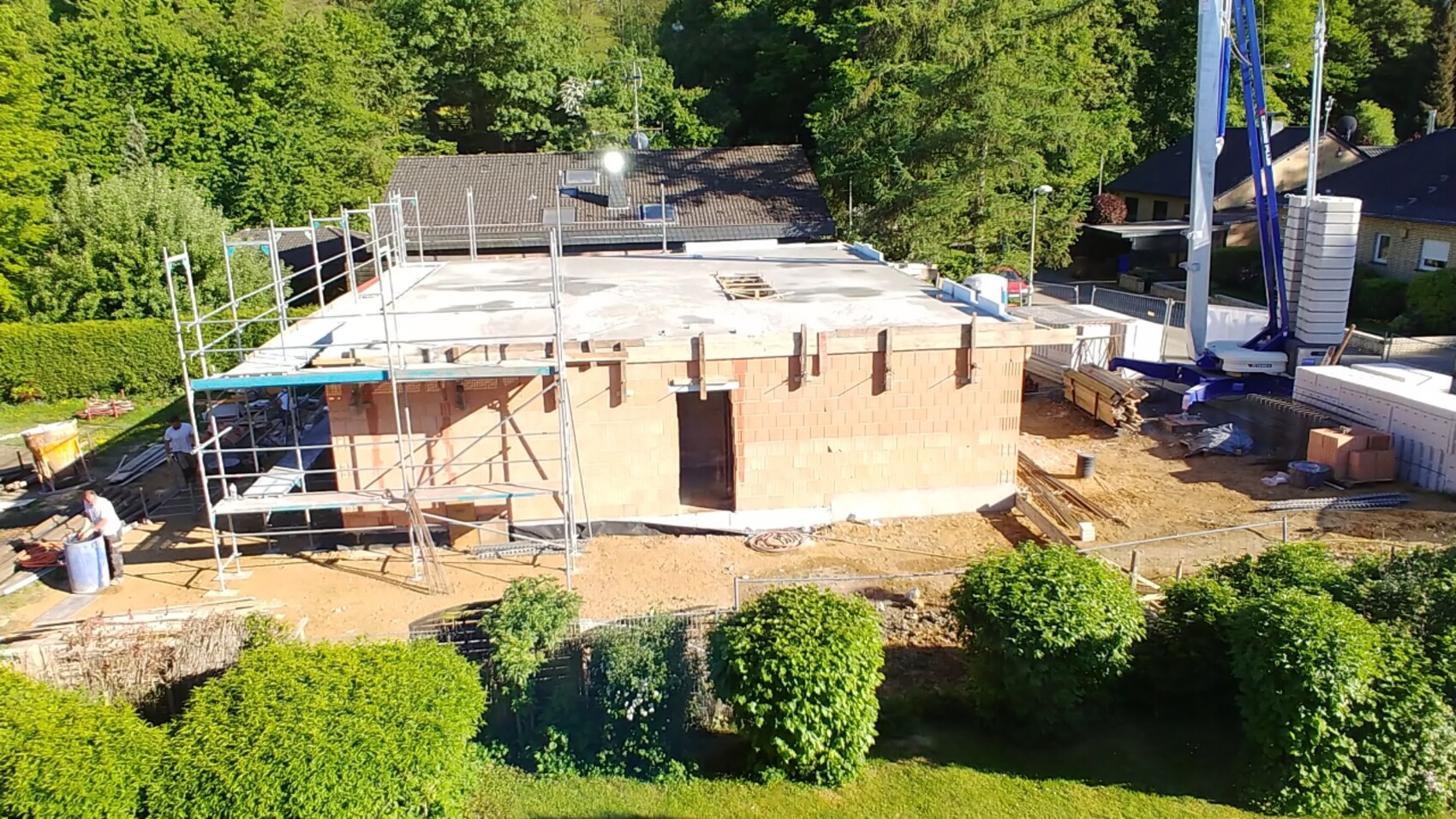 Unfertiges Backsteinhaus mit Gerüst, Arbeitern und Kran auf Baustelle.