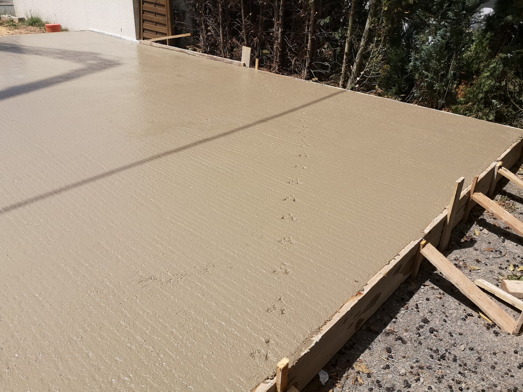 Frisch gegossene Betonplatte mit Holzformen; Fußspuren auf der Baustelle.