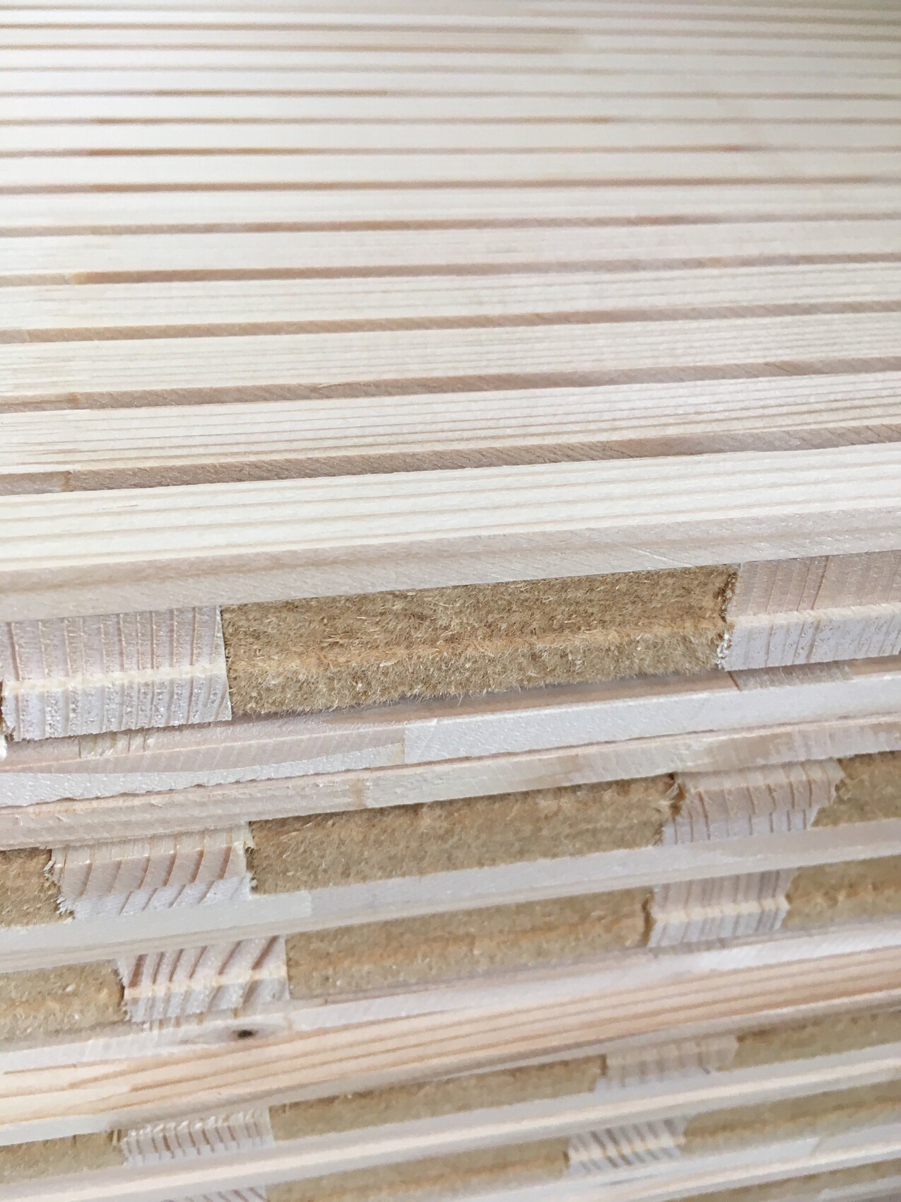 Stapel heller Holzbretter mit sichtbarer Maserung und Zwischenlagen.