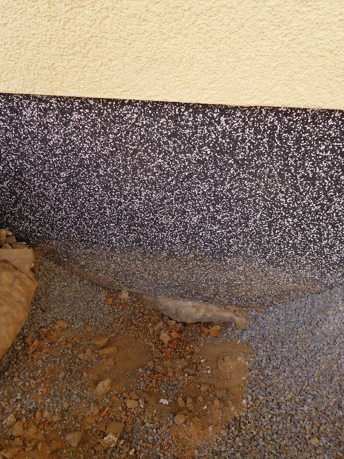 Außenwandfundament am Rohbau mit Kies, Erdreich und grobem Schotter.