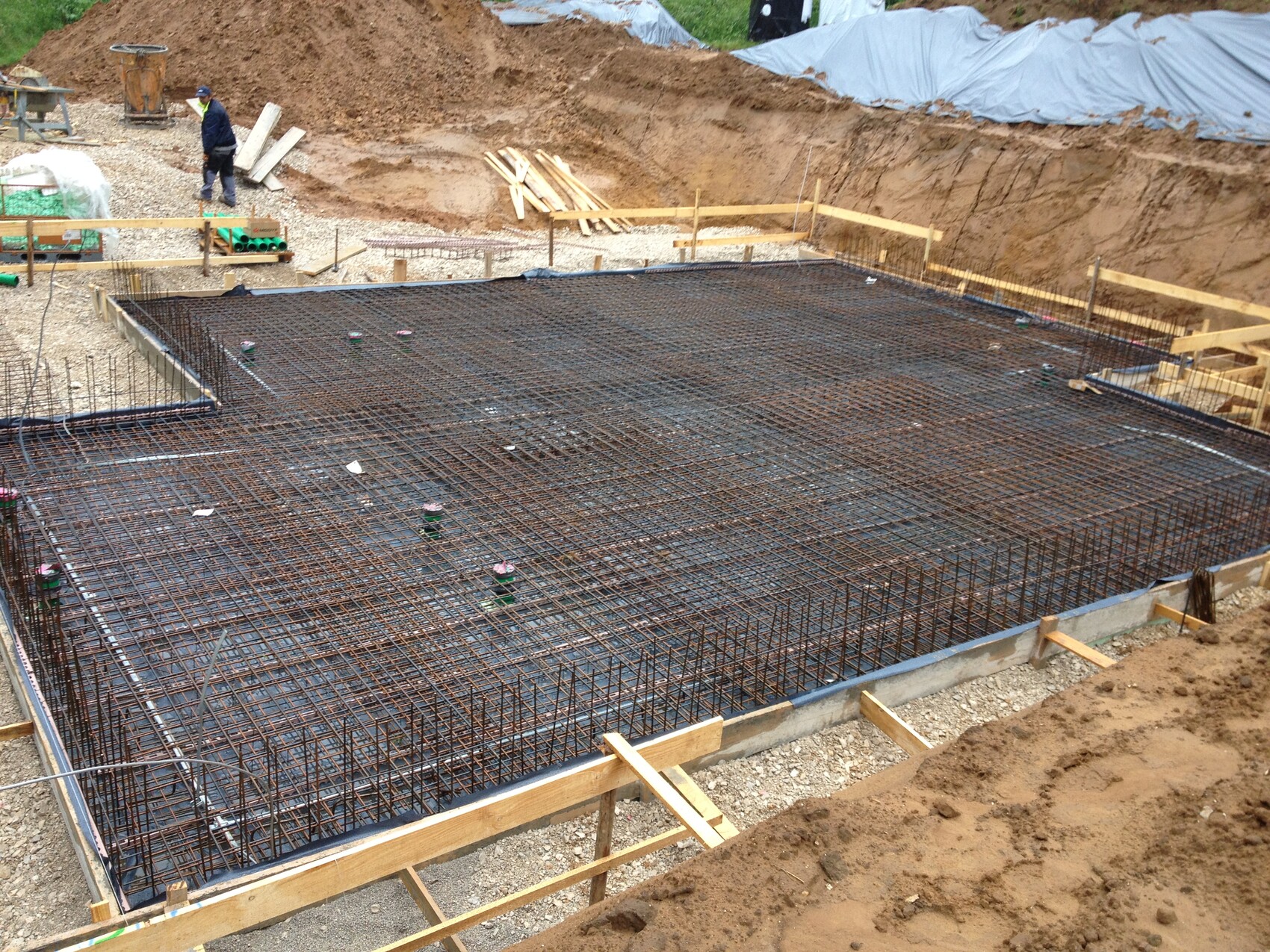 Fundament mit Bewehrungsstahlnetz auf der Baustelle, Arbeiter im Hintergrund
