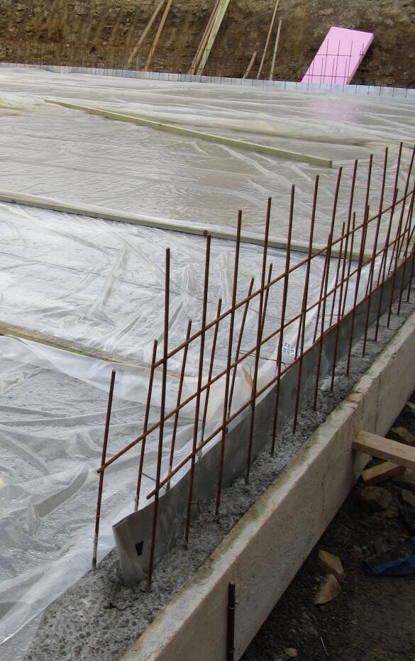 Baustellenfundament aus Beton mit Stahlbewehrung und Schutzfolie