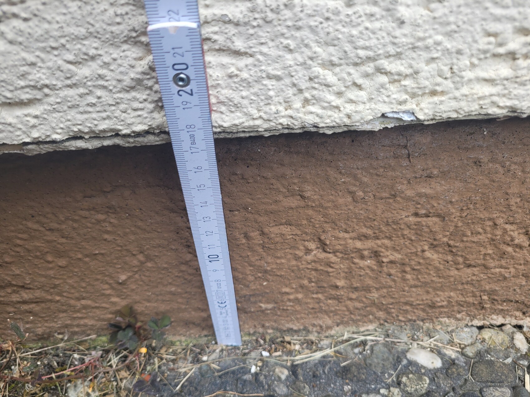 Messband steht senkrecht an einer rauen Wand und zeigt ca. 22 cm Höhe.
