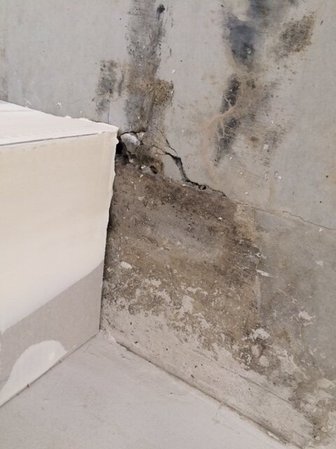 Riss im Betonfundament einer Innenwand mit Feuchtigkeit am Boden