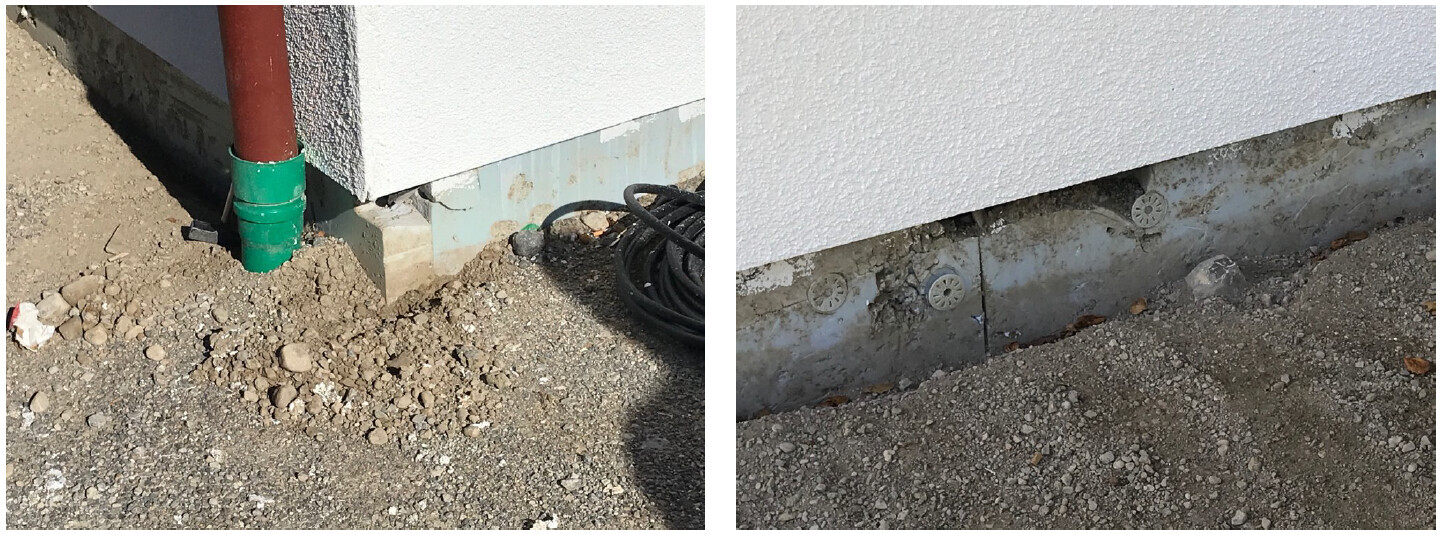 Unterer Wandbereich eines Gebäudes: rotes Fallrohr, grüner Sockel, Erdreich, Kies und Kabel.