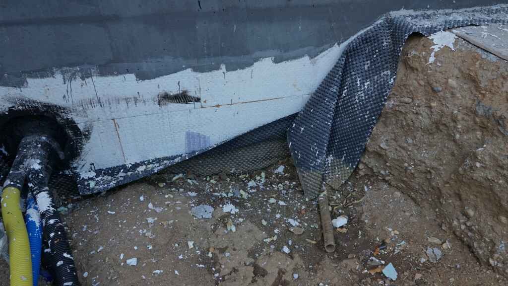 Baustelle mit Fundamentgräben, Erdreich und Abdichtungsfolie am Gebäudebereich