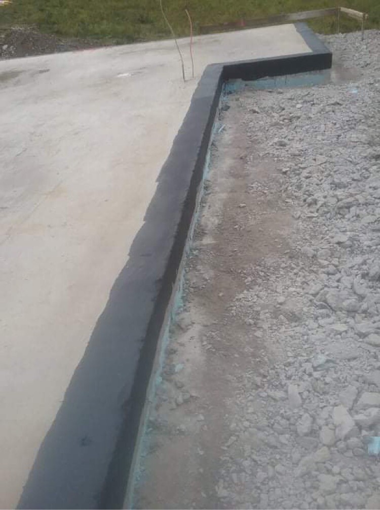 Frisch gegossene Betonplatte links, Kiesboden rechts, dunkle Randkante sichtbar.