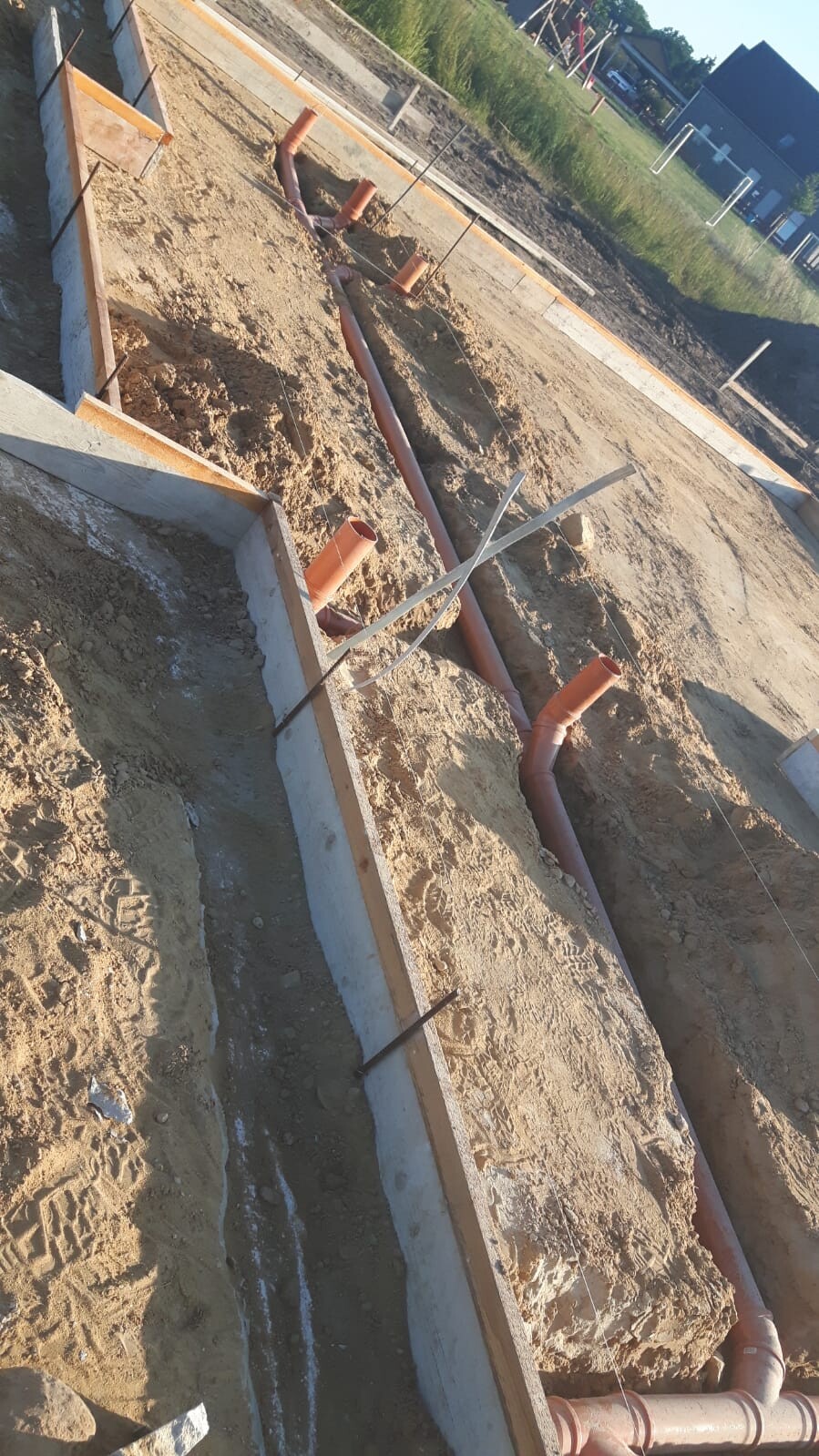 Baustelle mit Fundamentgräben und Rohren für Haustechnik