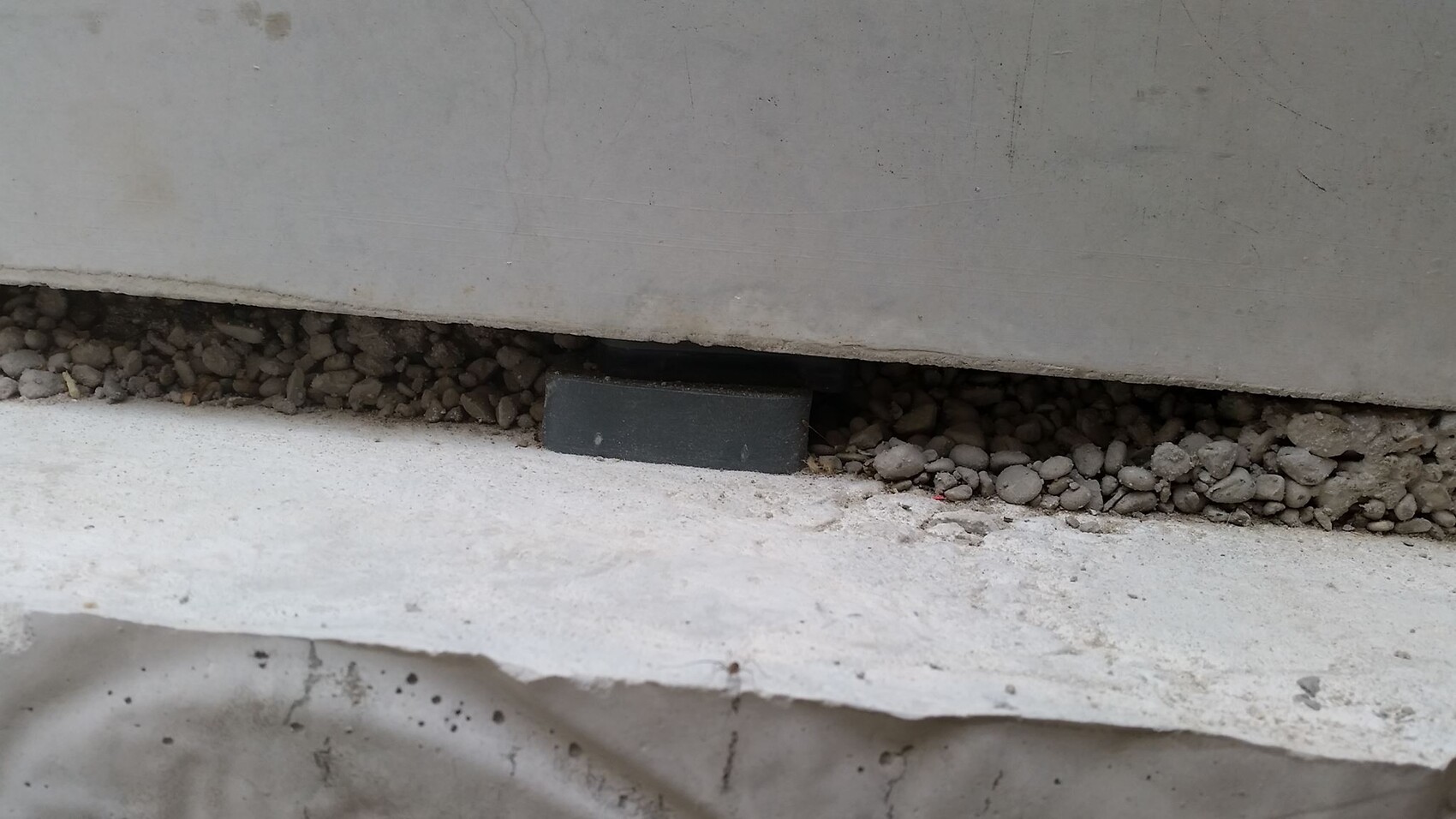 Betonfundamentplatte mit Kiesunterbau und einer kleinen schwarzen Stütze
