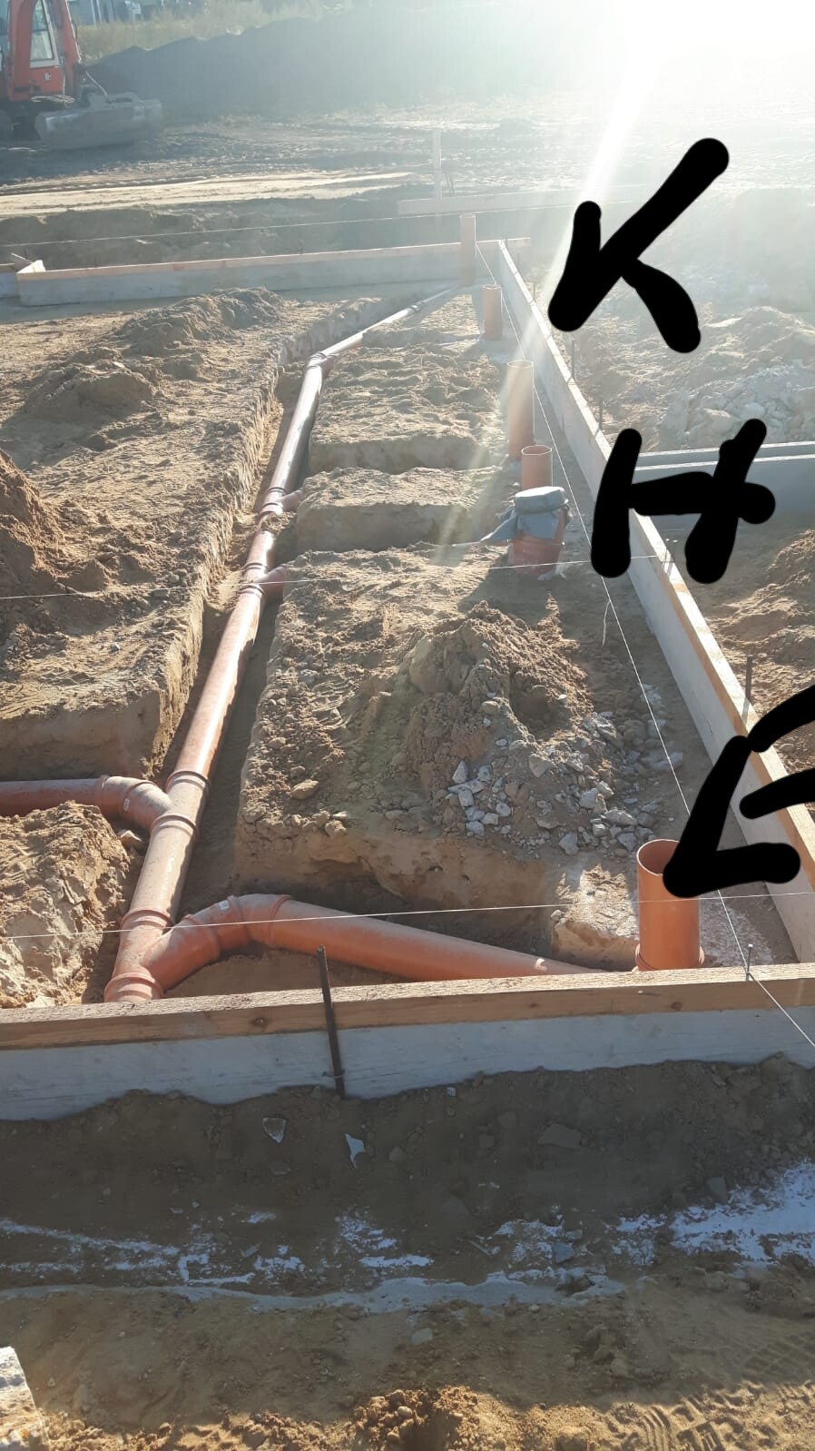 Baustelle mit Fundamentgraben und Rohrleitungen