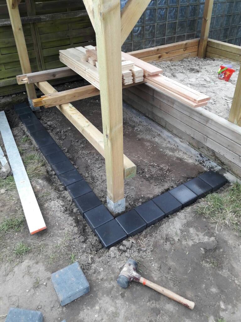 Fundamentbereich mit Pflastersteinen um Holzkonstruktion bei Bauarbeiten im Freien
