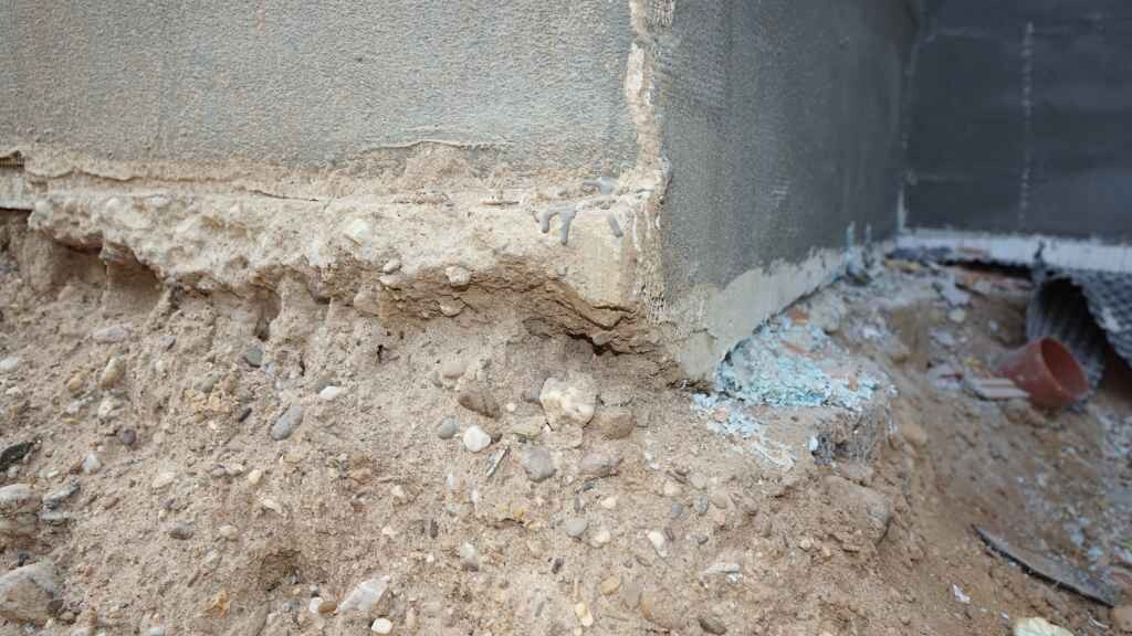 Offenes Fundament und Erdreich neben Gebäudewand bei Bauarbeiten
