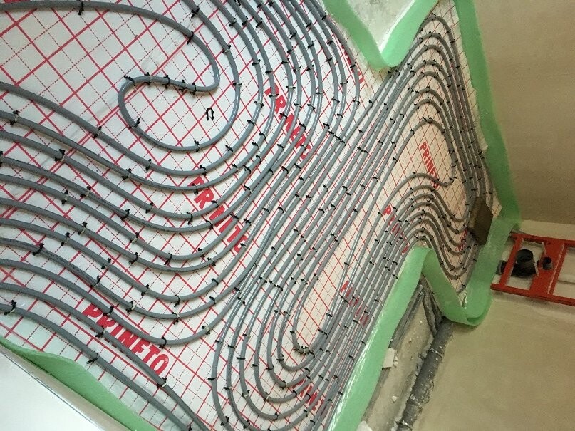 Spiralförmige Heizungsrohre auf Dämmplatte im Rohbau, Bodenheizung in Bauphase