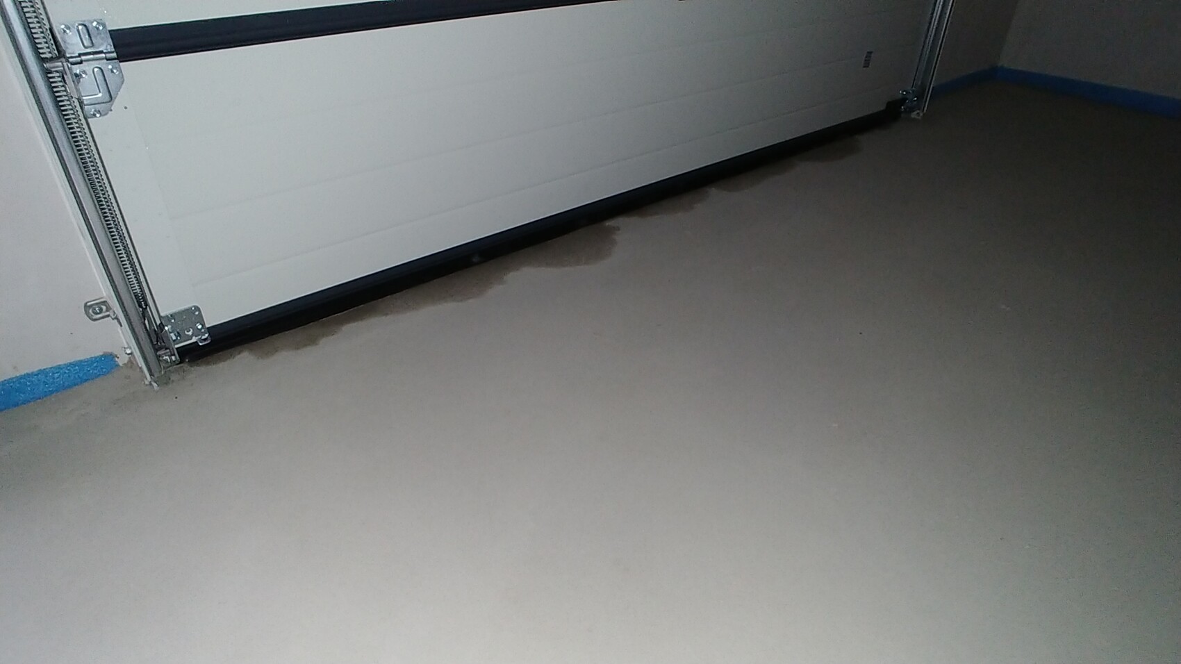 Innenansicht einer Garage mit Betonboden und Wasserflecken am Bodenrand